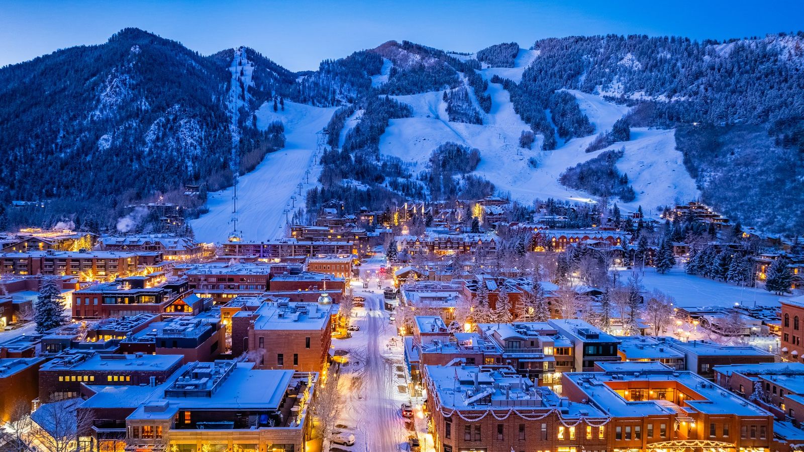 Calles de Aspen iluminadas al anochecer con la montana nevada detras